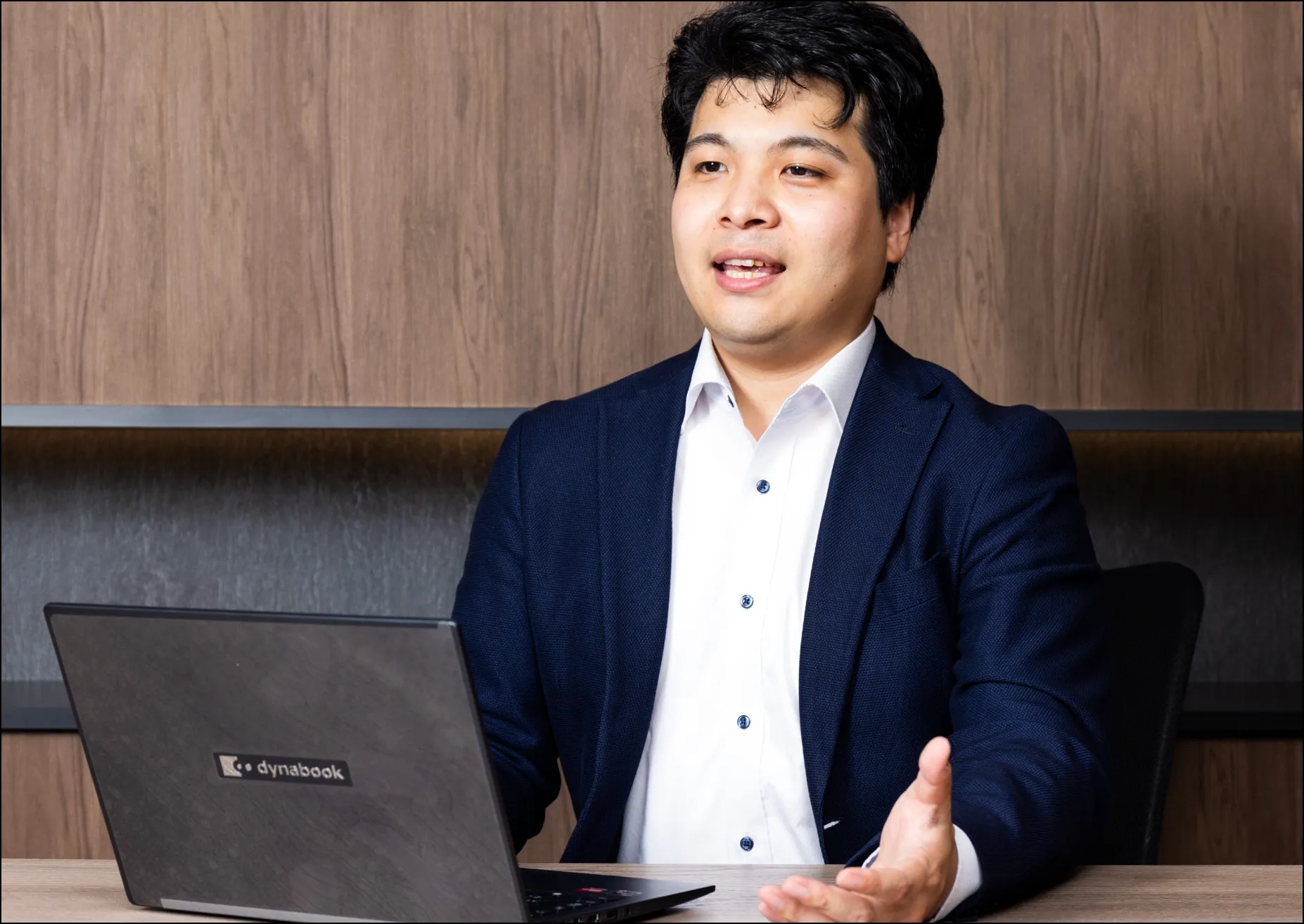 ノートパソコンを前に、にこやかに話をする男性社員