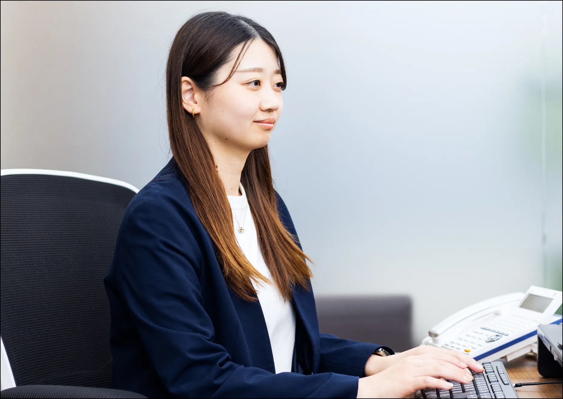 オフィスでデスクトップパソコンに向かい、キーボード入力を行う女性社員