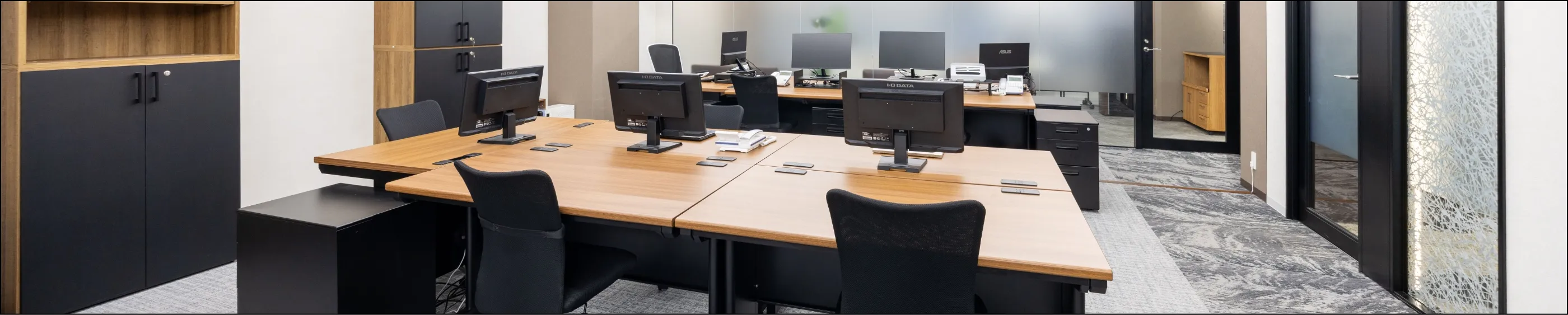 清潔感のあるモダンなフリーアドレス形式のオフィスデスクとPCモニターの並び